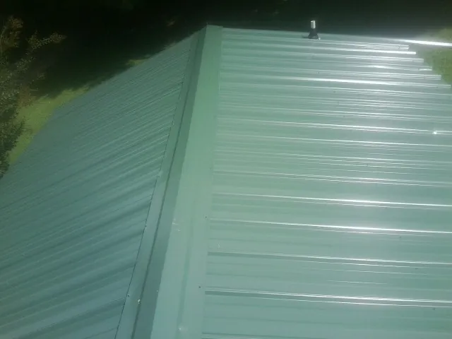 New green metal panels meeting at the ridge of a roof — Flat Roof Repair work by our crew in Carlton