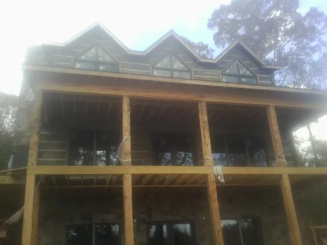 Dormers and porch framing on a large log home under construction — Roof Coating work by our crew in Carlton